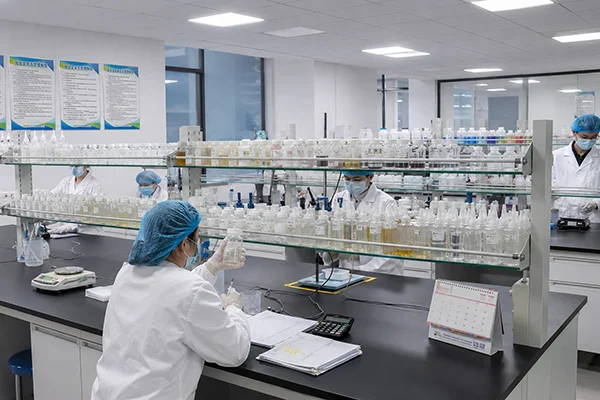 Group of scientists wearing lab coats and masks conducting tests on chemical samples in a modern laboratory setting.